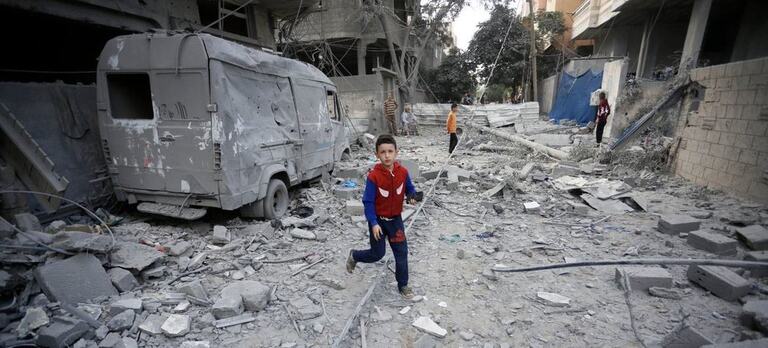 A boy runs through the destroyed streets of Gaza